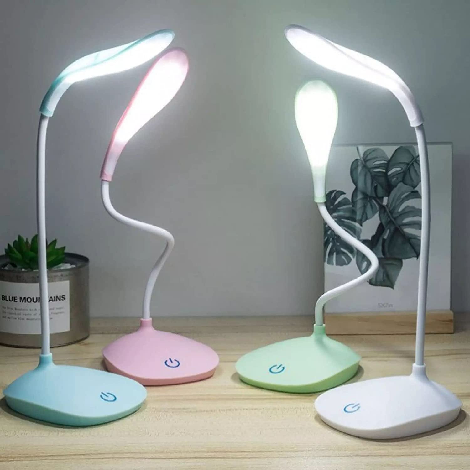 Four colorful desk lamps on a wooden surface with a neutral background.