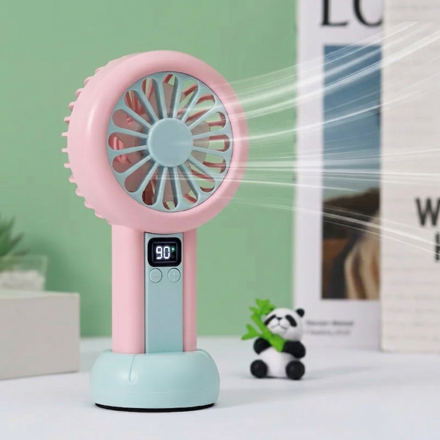 Colorful handheld fan with packaging on a wooden surface.