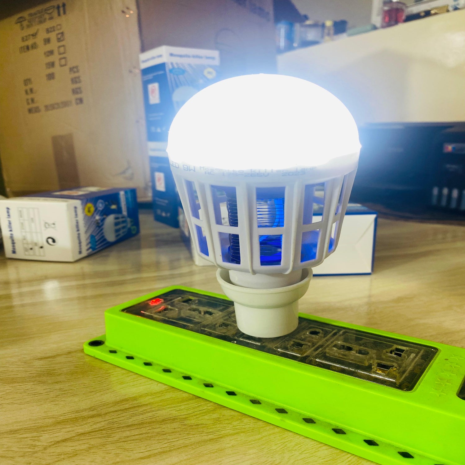 LED light bulb on a wooden surface with boxes in the background.