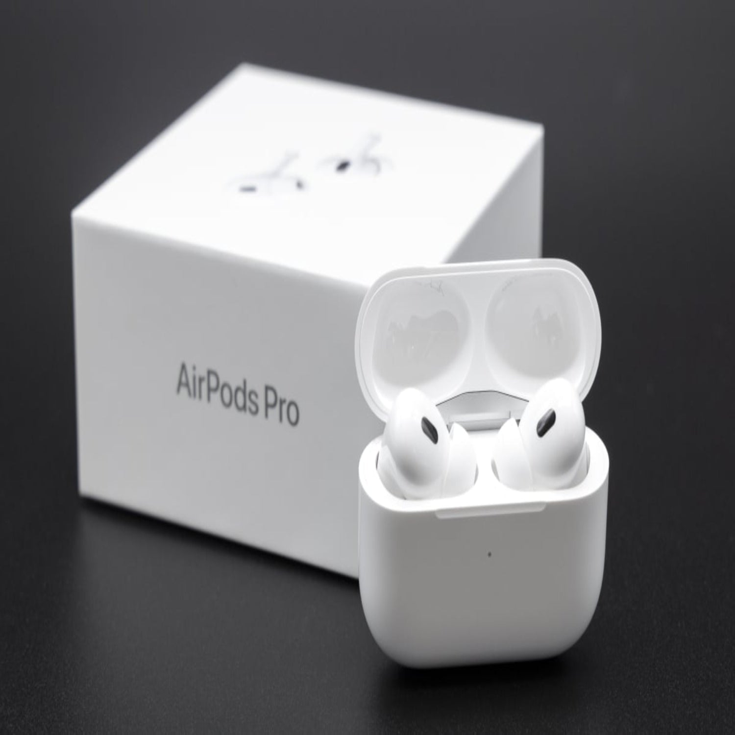 AirPods Pro in charging case with box on a dark background.