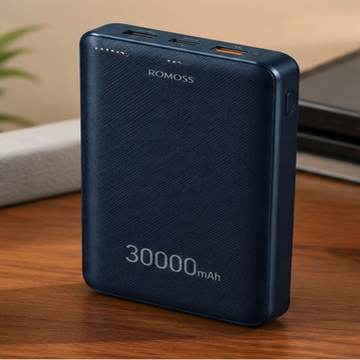 A dark blue ROMOSS portable power bank with a textured finish, standing on a wooden table. The front displays 'ROMOSS' and '30000 mAh' in white text, with USB-A and USB-C ports visible at the top.
